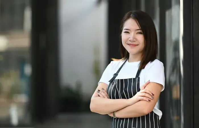Small business owner in an apron outside her shop, representing entrepreneurs growing with City Service Connect